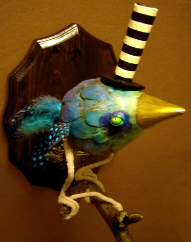 A fat blue bird in the shape of a teardrop, with beady yellow eyes, tiny feathered wings and tail, perched on a branch sprouting from a wooden plaque on the red wall background, and wearing a very very tall black and white striped tophat.